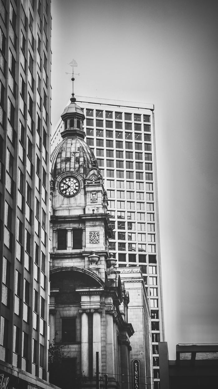 Services A classic clock tower juxtaposed against modern high-rise buildings in an urban cityscape.