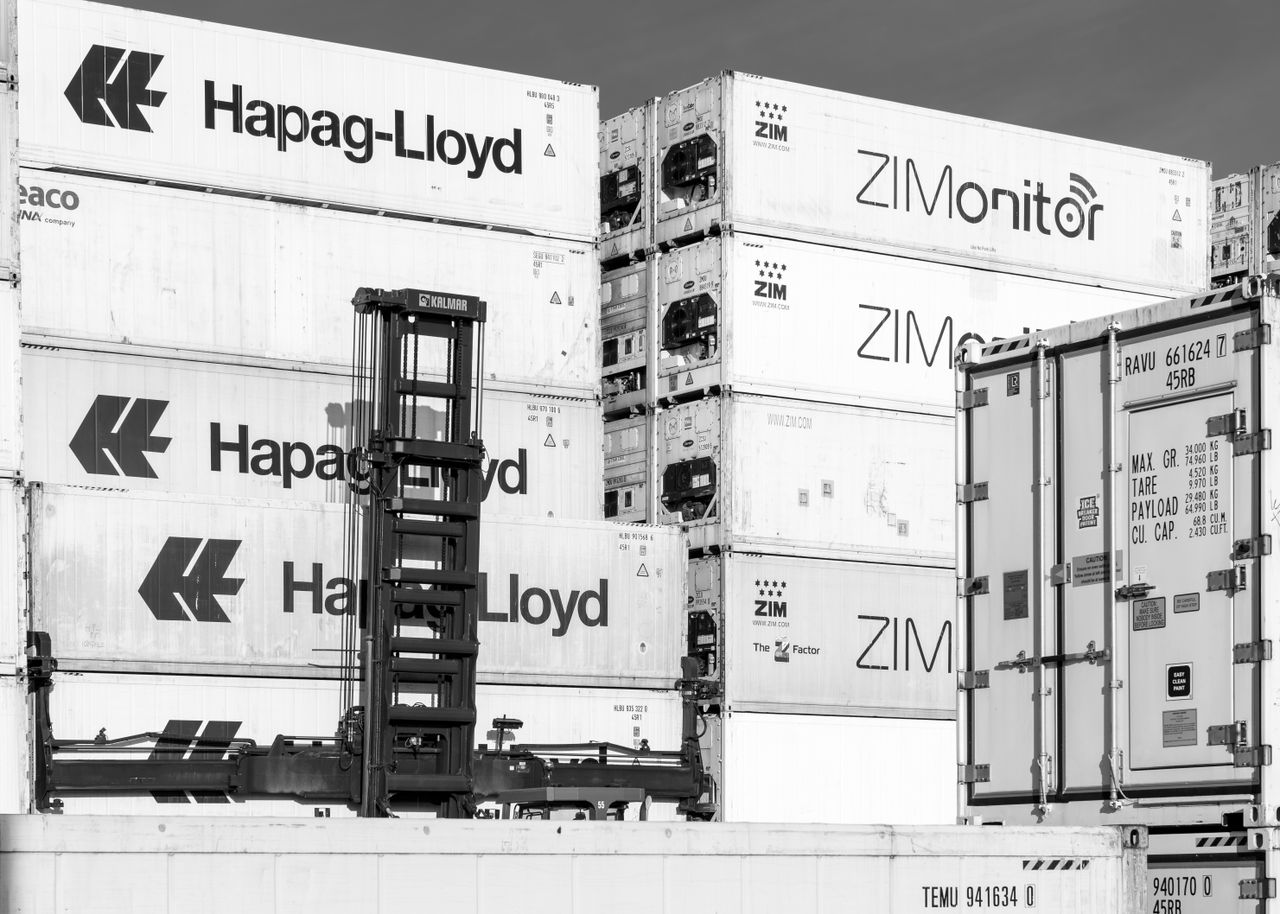Services Black and white image of stacked shipping containers in Hamburg, showcasing logistics and trade.