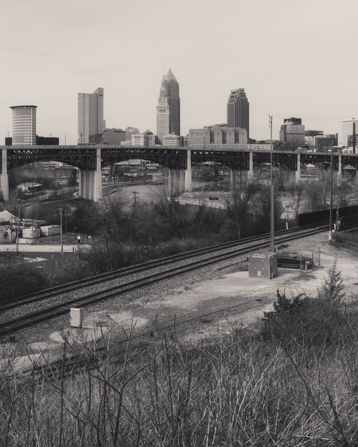 Monochrome view of Cleveland's skyline with urban railroads and overcast skies.
