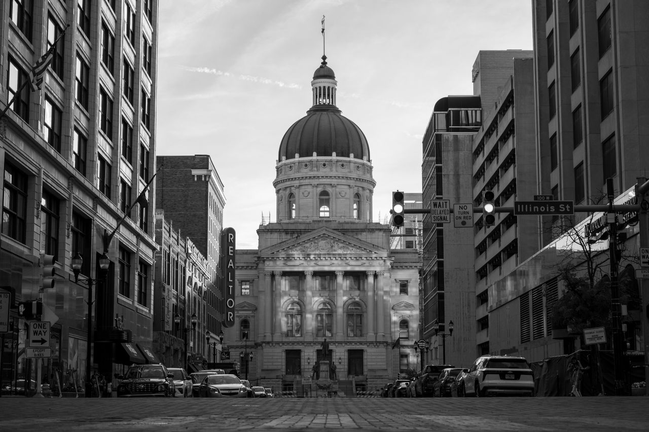 Services Black and white photo of a city street with a historic domed building at dusk.